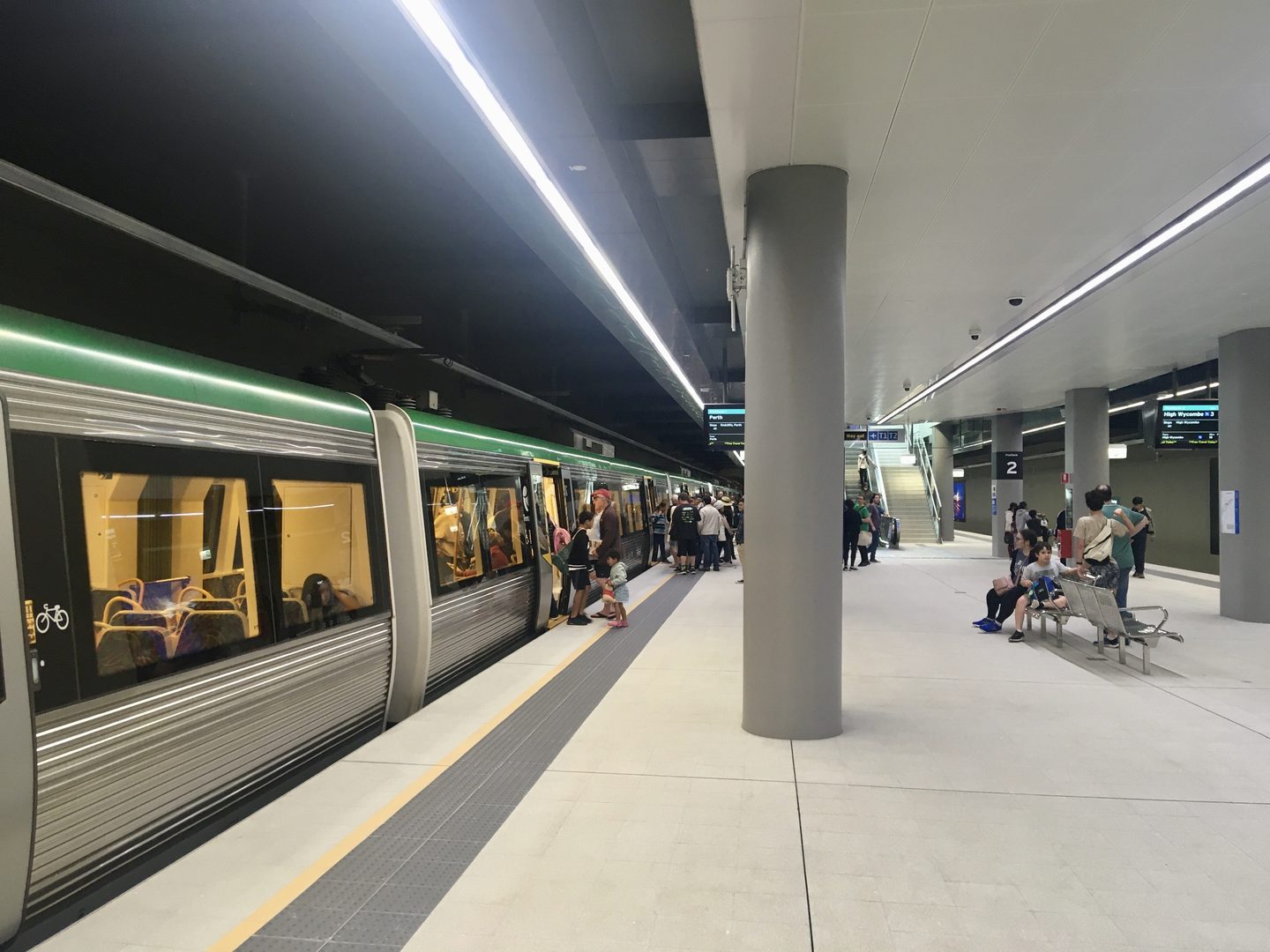 Un train Transperth à quai à Airport Central Station, avec des voyageurs sur le quai.