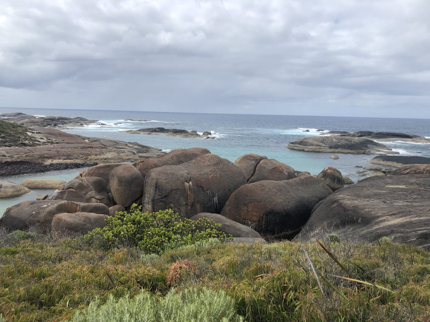 Rundliche Granitformationen bei Elephant Rocks am Meer unter bewölktem Himmel.