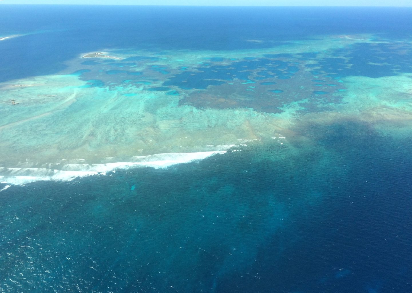 An aerial view of turquoise shallows, darker reef patches and breaking waves at Morning Reef in the Houtman Abrolhos.