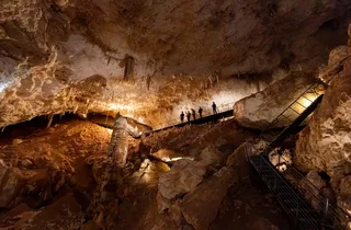 Visitors walking through Jewel Cave on a raised path among illuminated formations
