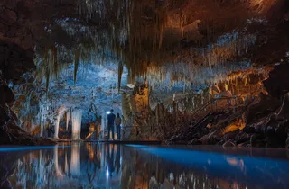 Interior of Lake Cave with a reflective underground pool and illuminated formations